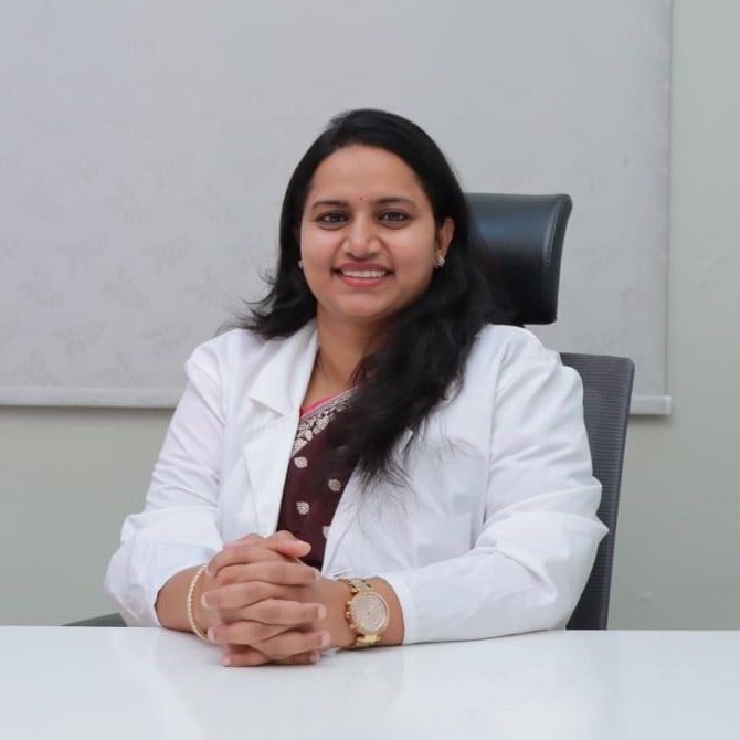 Dr. Palaparthi Lalitha Devi, seated at her desk, in a white coat